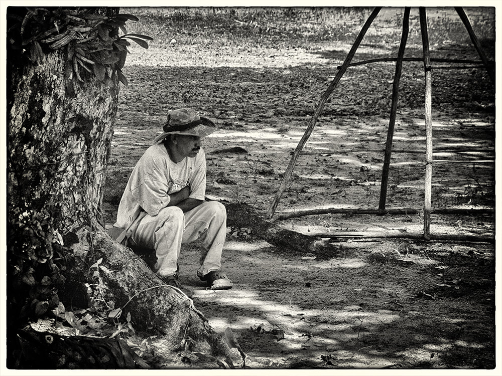 man in hat, sitting by tree, black and white